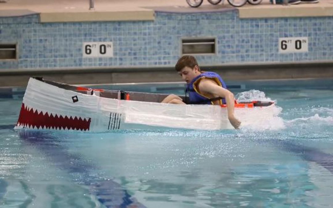 High school students race boats made of cardboard and duct tape